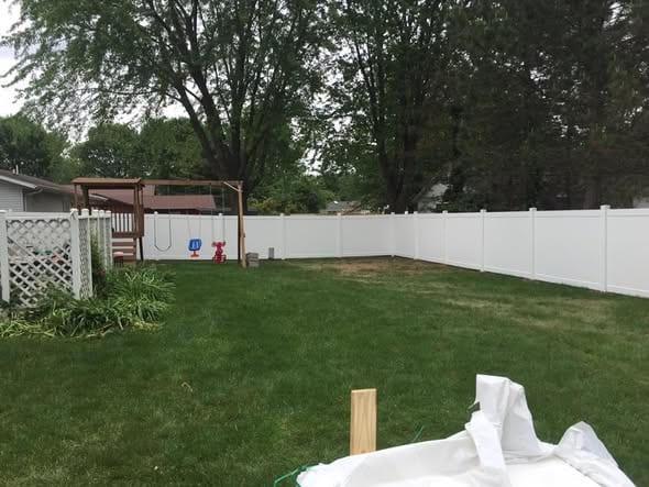 White vinyl privacy fence enclosing a backyard with a playset