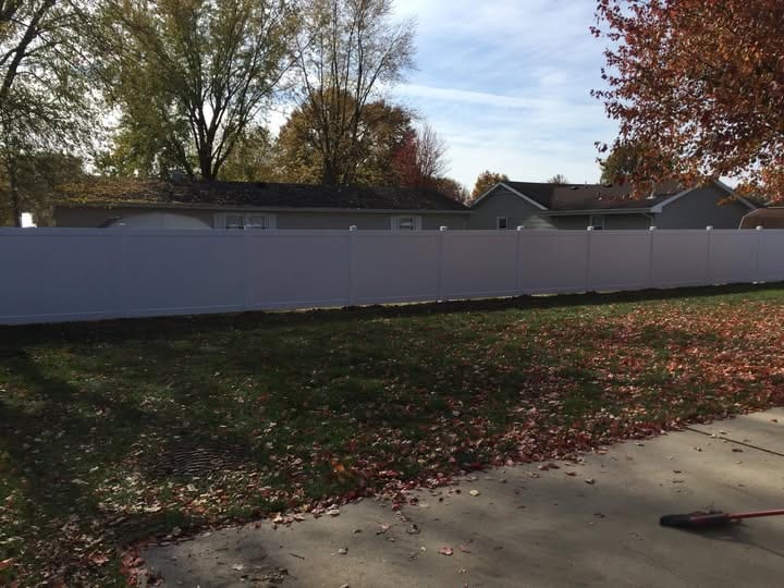Long run of white vinyl privacy fence along a residential street