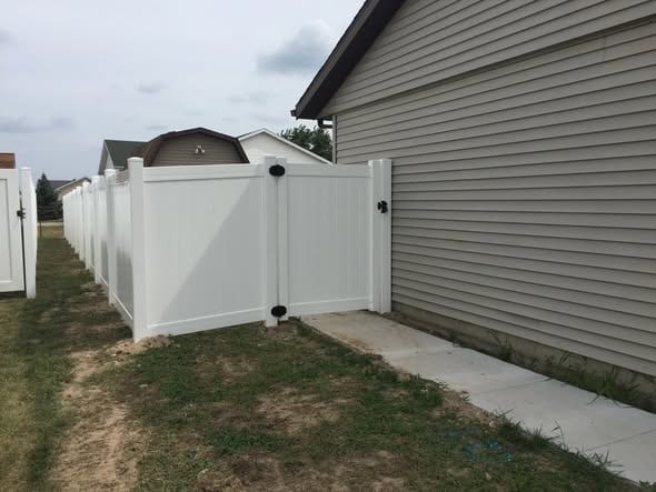 White vinyl fence with walk gate beside a detached garage