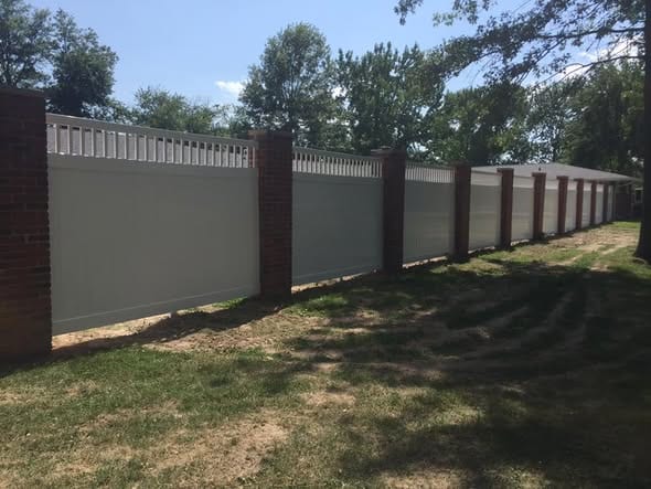Vinyl privacy fence panels set between brick masonry pillars