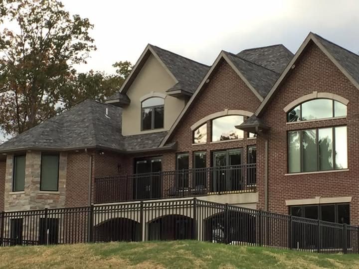 Black ornamental aluminum fence at a brick estate home