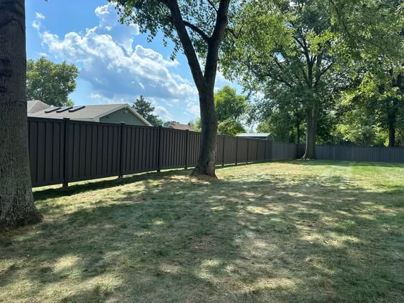Dark composite privacy fence shading a backyard