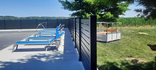Black-frame horizontal composite fence beside a pool deck